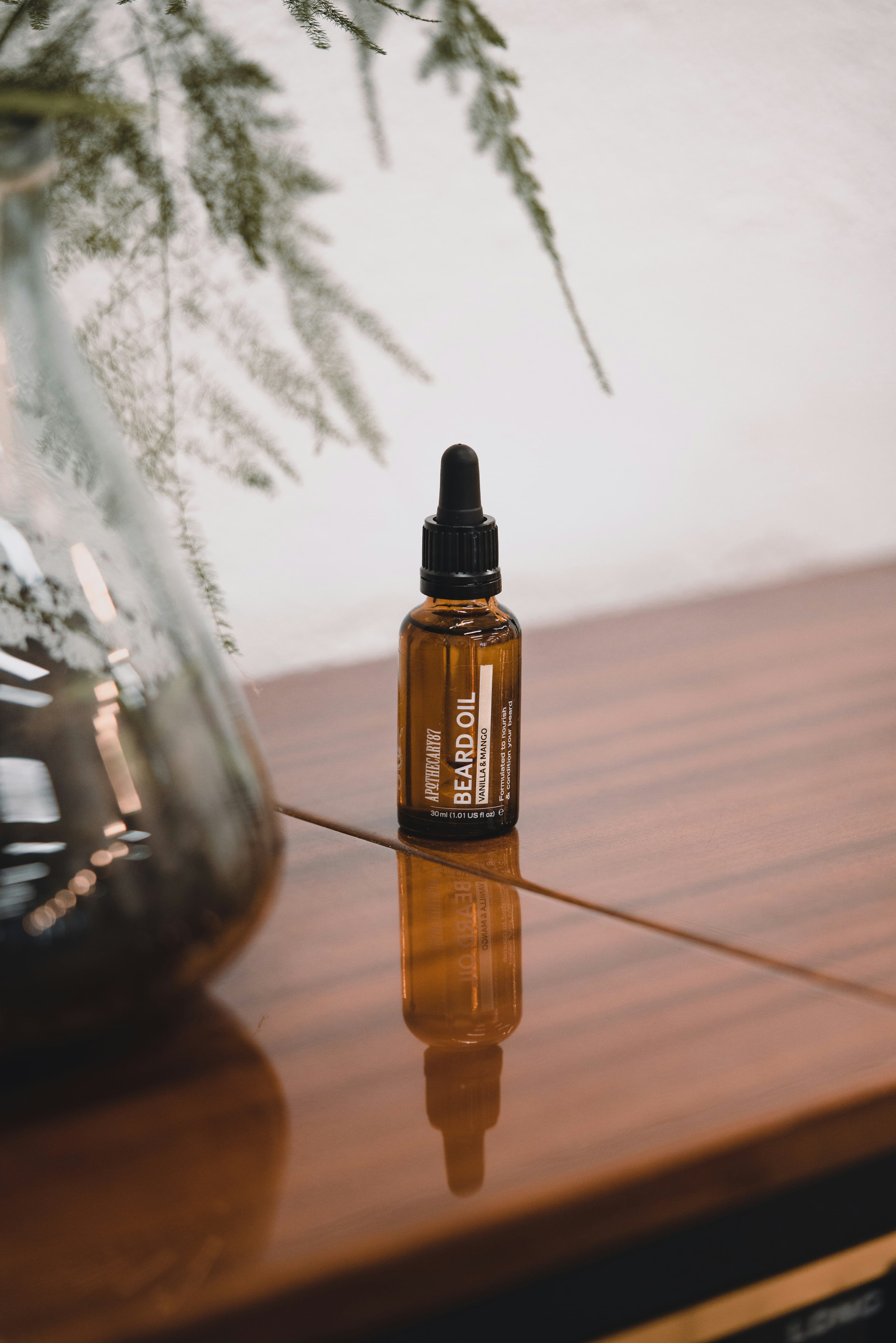 Amber bottle of hair oil beside a wooden comb